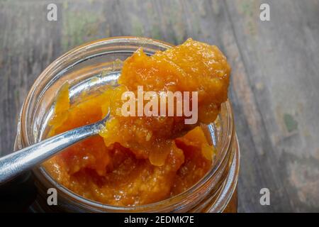 Cucchiaio pieno di marmellata di arance domestiche fresche sopra il vaso aperto. Juicy naturale . Bucce anche all'interno. Foto Stock