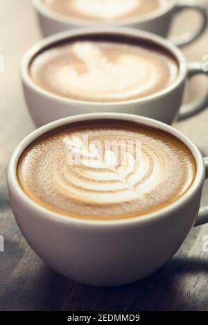 Primo piano del bellissimo caffè rosetta pattern latte art le tazze sul tavolo di legno Foto Stock