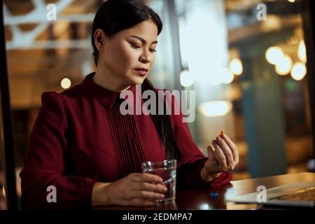 Giovane donna asiatica seria che guarda la medicina Foto Stock