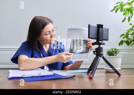 Medico femminile sicuro e maturo che fa video consultazione con smartphone Foto Stock