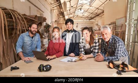 Gruppo di artigiani come falegnami squadra utilizzando computer portatile in officina Foto Stock