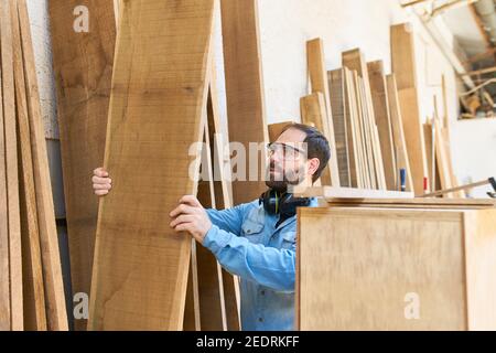 Artigiano come falegname o falegname con legno massello tavola nel negozio di legno Foto Stock