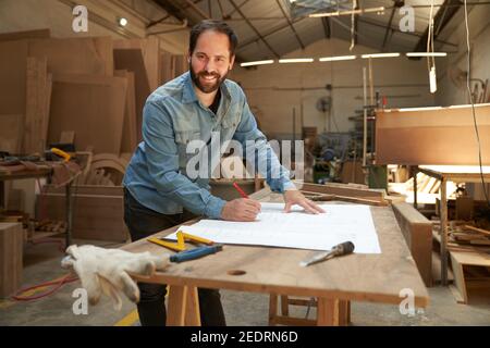 Il fondatore di start-up e l'architetto creativo disegnano una pianta dentro l'officina Foto Stock