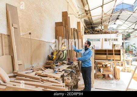 Artigiano come falegname nel negozio di legno del falegnameria con molto legno Foto Stock