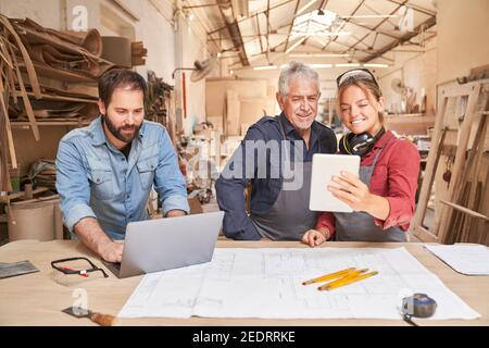 Artigiani squadra con computer in un laboratorio di falegname in un artigianato di medie dimensioni Foto Stock