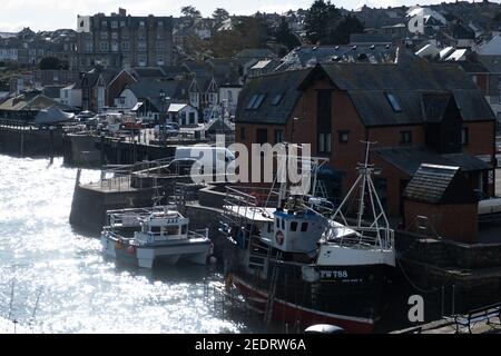 Scena retroilluminata con acque scintillanti della città di Padstow come sfondo per imbarcazioni da pesca ormeggiate e altre imbarcazioni. Una barca su cui si sta lavorando. Foto Stock