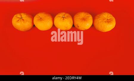 5 arance mandarine per la celebrazione e la decorazione del Capodanno cinese su sfondo rosso Foto Stock