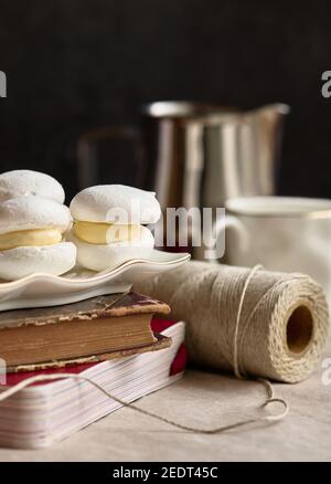 Piatto con torta meringa con panna in piedi su una pila di libri, profondità di nitidezza poco profonda Foto Stock