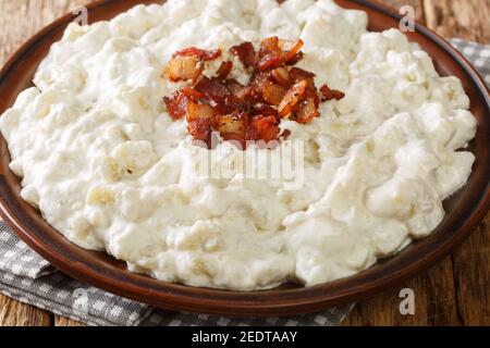 Gnocchi di patata grattugiata slovacco Halusky con formaggio e pancetta chiodata nel piatto sul tavolo. Orizzontale Foto Stock