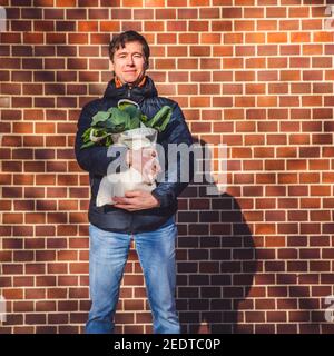 Foglie fresche in sacchetto organico in mano dell'uomo, stile di vita sano. Shopping con borsa eco shopper al mercato di strada, concetto ecologico Foto Stock