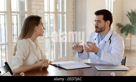 Giovane donna focalizzata che ascolta la consulenza medica professionale. Foto Stock