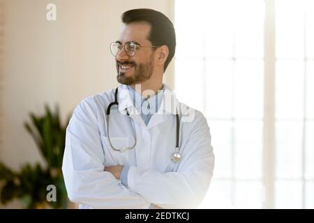 Sorridente giovane bel medico professionista che guarda a distanza. Foto Stock