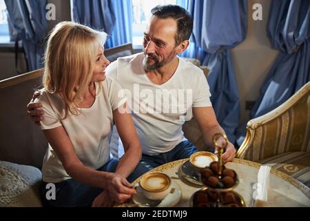 Felice uomo abbracciando bella donna mentre sedeva sul divano Foto Stock