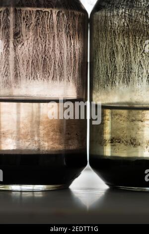 Sedimentazione di pigmento tonale di olio nero in minerale di solvente organico l'olio si deposita con macchie di pigmenti all'interno Di vaso di vetro RGB Foto Stock