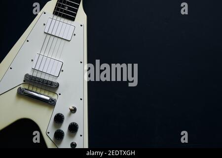 Vista dall'alto ripresa di una chitarra elettrica bianca a V su sfondo scuro e grunge. Foto Stock