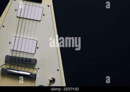 Vista dall'alto ripresa di una chitarra elettrica bianca a V su sfondo scuro e grunge. Foto Stock