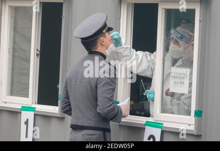 Seoul, Corea del Sud. 14 Feb 2021. Un'infermiera che indossa una tuta protettiva personale (PPE) preleva un campione di tampone da un cadetto dell'Accademia militare di Corea durante un test COVID-19 gratuito in una clinica di improvvisazione. Credit: SOPA Images Limited/Alamy Live News Foto Stock