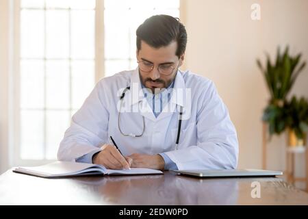 Focalizzato giovane medico maschile in occhiali che lavorano in ufficio. Foto Stock