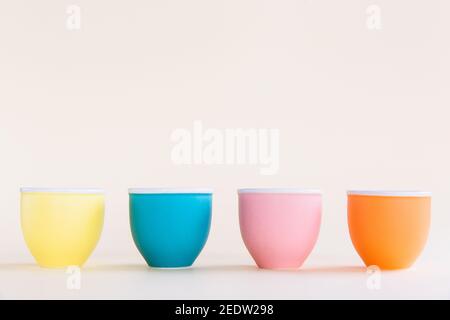 Coppe colorate su sfondo pastello, spazio copia. Concetto minimo di Pasqua. Primo piano Foto Stock