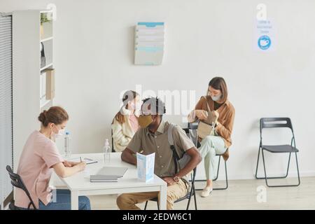 Vista grandangolare dell'infermiere di sesso femminile che registra pazienti in attesa in linea presso il centro medico, spazio di copia Foto Stock