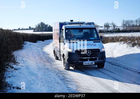 tesco home delivery furgone sulla corsia di campagna coperta di neve, norfolk settentrionale, inghilterra Foto Stock