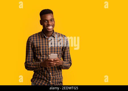 Ritratto di un ragazzo nero felice con smartphone in mani sorridenti alla telecamera Foto Stock