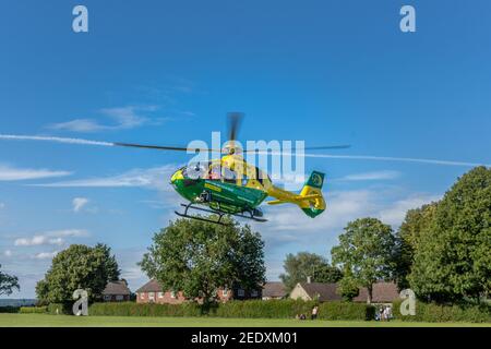 L'Hampshire e Isola di Wight elicottero ambulanza aerea prendere fuori da un campo da gioco villaggio in un pomeriggio estivo Foto Stock