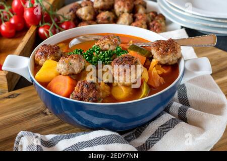 Zuppa di verdure con cavolo e polpette in una ciotola sul tavolo da cucina. Vista frontale con sfondo sfocato Foto Stock