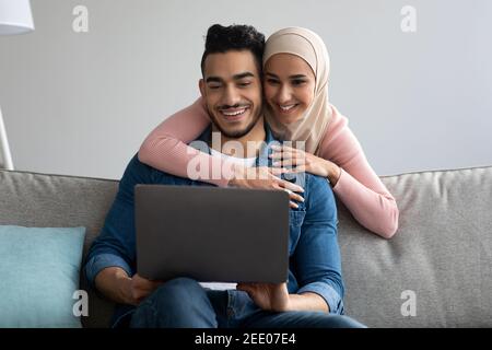 Allegra coppia araba che chiama gli amici tramite il computer portatile Foto Stock