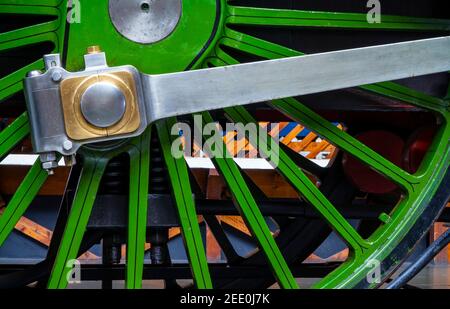 Vista ravvicinata dei raggi dipinti di verde sulla ruota di una locomotiva a vapore. Foto Stock