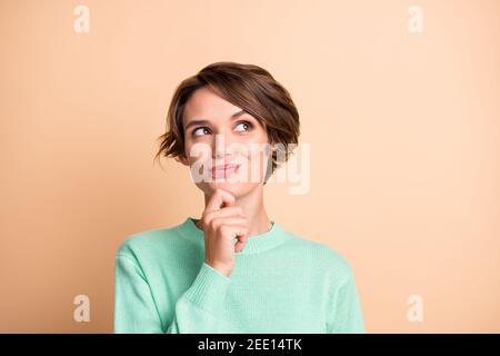 Ritratto di giovane bella sorridente pensieroso dreamy ragazza sguardo copyspace pensare tenere la mano mento isolato su sfondo di colore beige Foto Stock