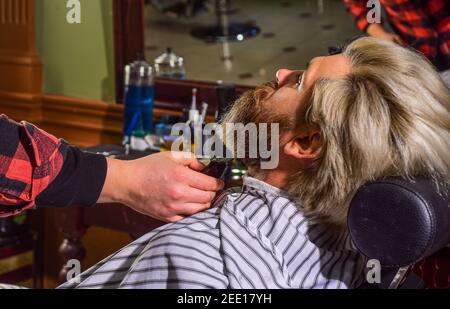 Mantenere la forma della barba. Fate crescere la barba e i baffi. Uomo al barbiere. Parrucchiere. Barbiere professionale e cliente. Rifinitura della barba in primo piano. Migliora la tua esperienza di taglio dei capelli. Capelli del viso. Foto Stock