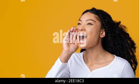 Concetto di annuncio. Giovane afroamericana gridando forte allo spazio di copia Foto Stock