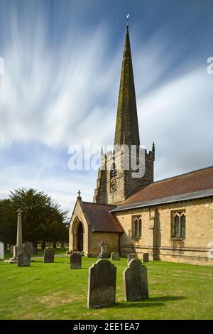 Esterno della storica chiesa di St. Edith (memoriali dei cantieri, portico, guglia alta e cielo blu) - Bishop Wilton, East Riding of Yorkshire, Inghilterra, UK. Foto Stock