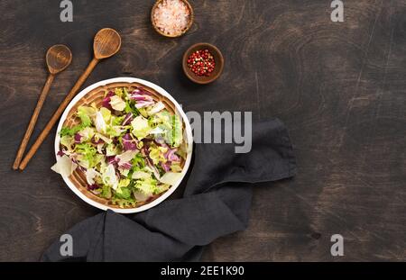 Fresco verde primavera mix insalata foglie in legno colander su sfondo rustico di legno. Messa a fuoco selettiva. Foto Stock