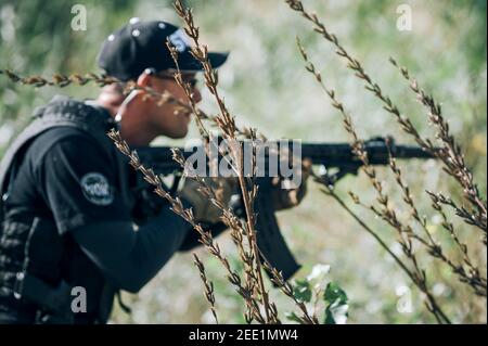 Soldato militare militare in azione tattica di combattimento tiro da fucile mitragliatrice. Tiro e armi. Campo di ripresa all'aperto Foto Stock