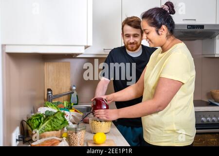 Giovane coppia di razza mista che prepara hummus vegano Foto Stock