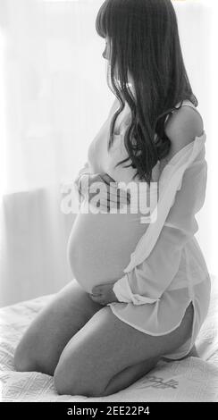 Immagine in bianco e nero di una donna incinta che tiene le mani Foto Stock