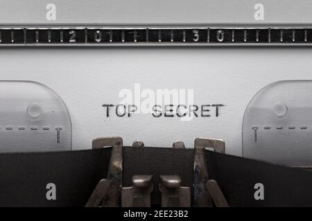Scrivere il testo TOP SECRET sulla macchina da scrivere manuale d'epoca. Primo piano di scrive parole su white paper. Scatto in macro. Foto Stock