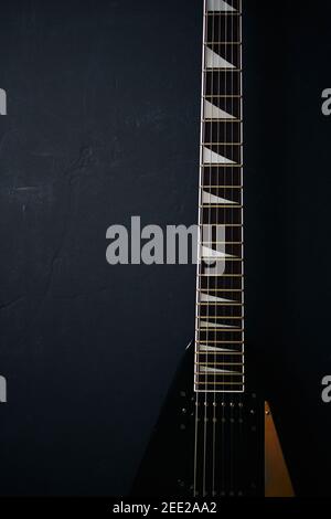 Vista dall'alto ripresa di una chitarra elettrica a V nera su sfondo scuro grunge con spazio di copia Foto Stock