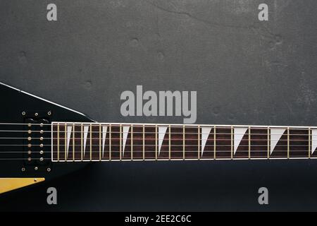 Vista dall'alto ripresa di una chitarra elettrica a V nera su sfondo scuro grunge con spazio di copia Foto Stock