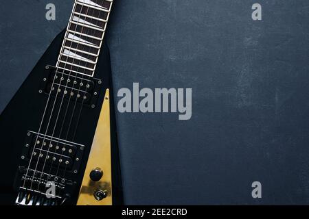 Vista dall'alto ripresa di una chitarra elettrica a V nera su sfondo scuro grunge con spazio di copia Foto Stock