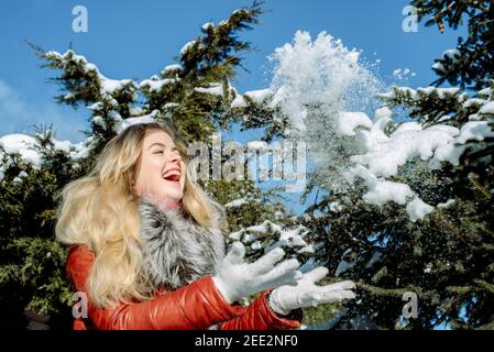 Emozionale ragazza dagli occhi blu che soffia la neve nelle mani. Inverno gelido. Foto Stock