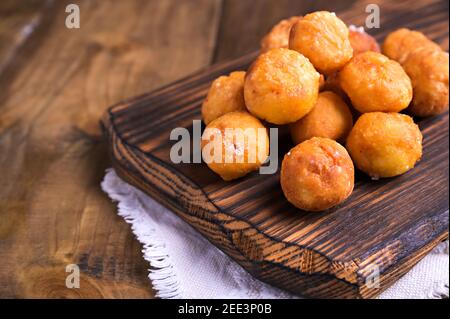 castagnole al forno con zucchero in polvere su fondo di legno. Street food, biscotti rotondi con zucchero per il carnevale di Venezia. Dolci tradizionali nel periodo del carnevale in italia. Spazio fotocopie Foto Stock