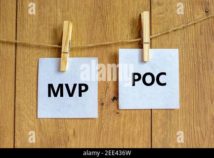 Simbolo MVP vs POC. Stope di legno con carta bianca. Parole MVP, prodotto minimo vitale e POC, prova di concetto. Bellissimo sfondo in legno. Busi Foto Stock