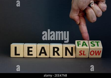 Simbolo di apprendimento lento o veloce. L'uomo d'affari gira i cubetti di legno e cambia le parole 'imparare lento' a 'imparare veloce'. Splendido sfondo grigio, spazio per la copia. Busin Foto Stock