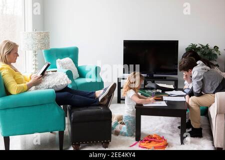 La famiglia si rilassa e fa i compiti nel proprio soggiorno. Foto Stock