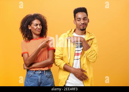 Due migliori amici che si divertono a puntare l'uno verso l'altro con un sorriso gioioso e simpatico come se si incolpano a vicenda giocosamente. Cute femmina che guarda Foto Stock