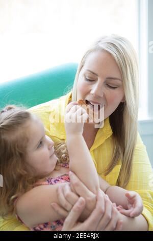 Una bambina le dà un morso biscotti al cioccolato Foto Stock