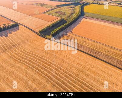 Veduta aerea di una stretta strada di campagna asfaltata grigia, che attraversa un paesaggio con campi e prati. Foto Stock